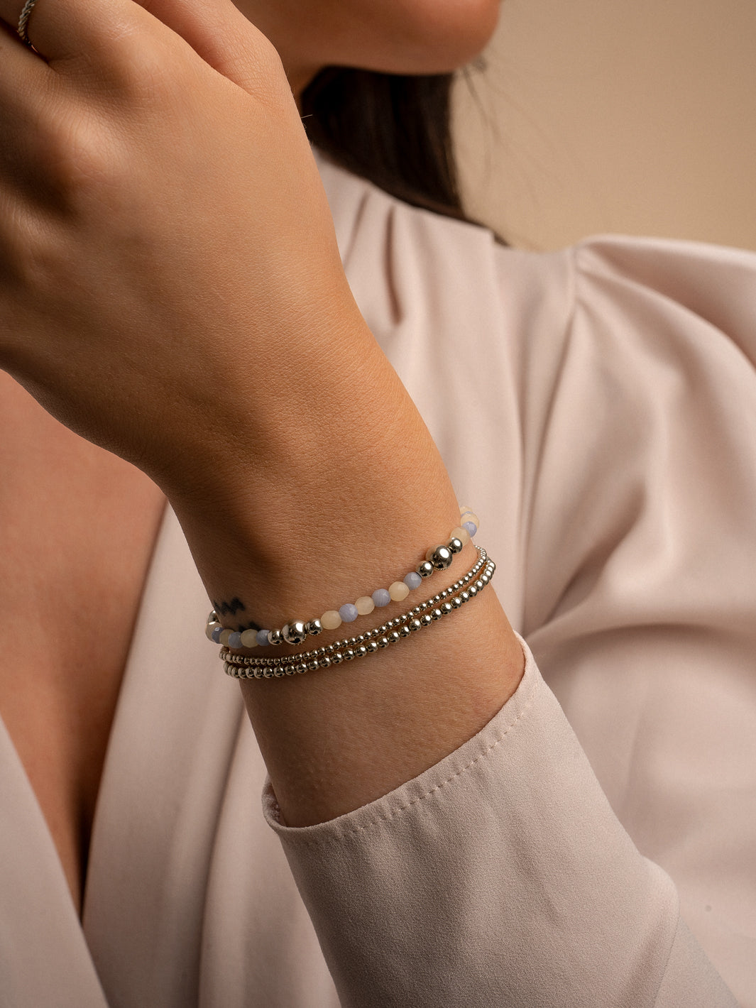 Zilveren armbanden stack gedragen om een vrouwen pols met beige agaat edelsteen en blue lace agaat 